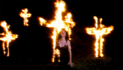 A woman dancing in front of burning crosses