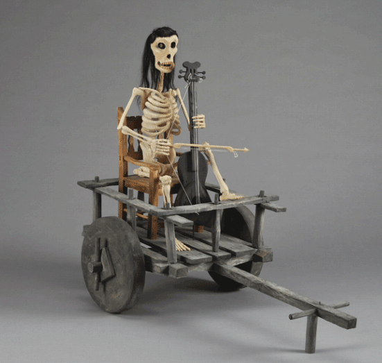 a skeleton fiddles in a farm cart